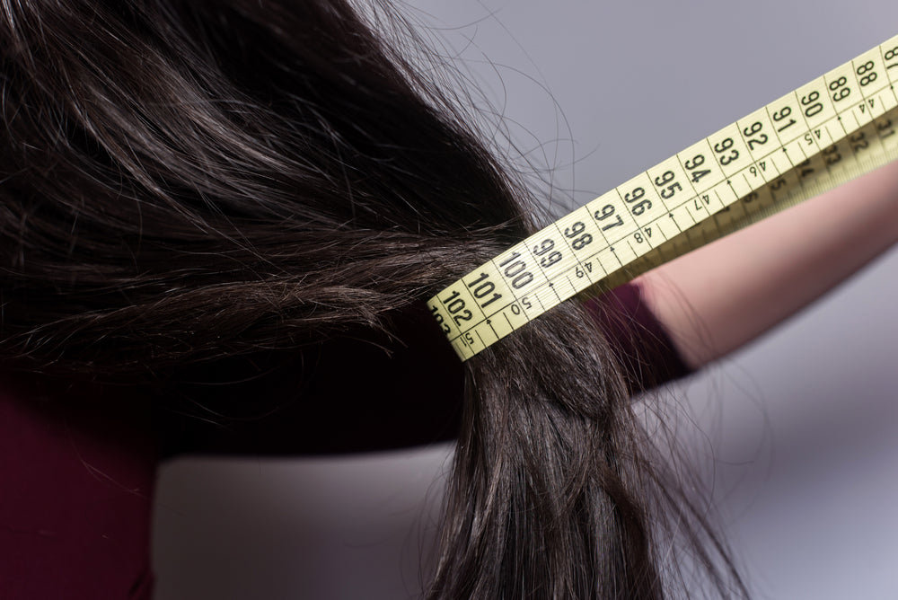 Mounjaro hair loss illustrated by a woman measuring the thickness of her hair