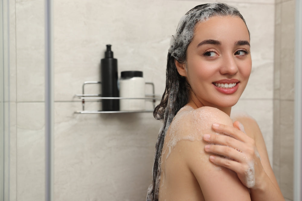 Woman washing her hair with caffeine shampoo in the shower.