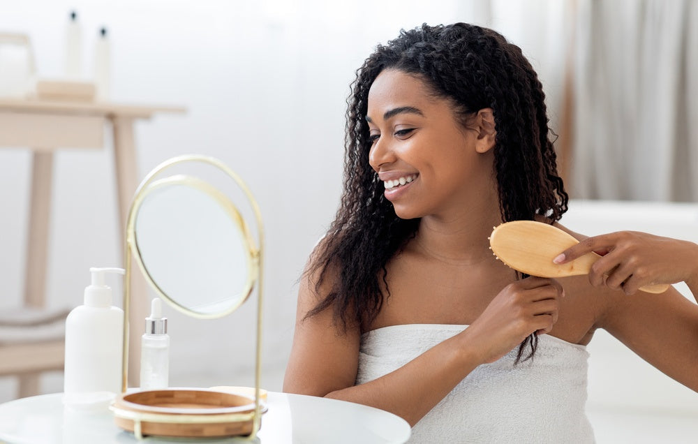 Woman brushing her natural curly hair as part of a hair longevity routine