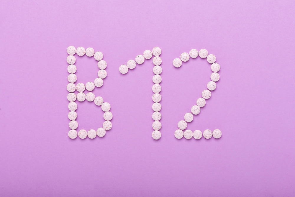 Tablets spelling B12 on a pink background, illustrating vitamin B12 and hair loss.